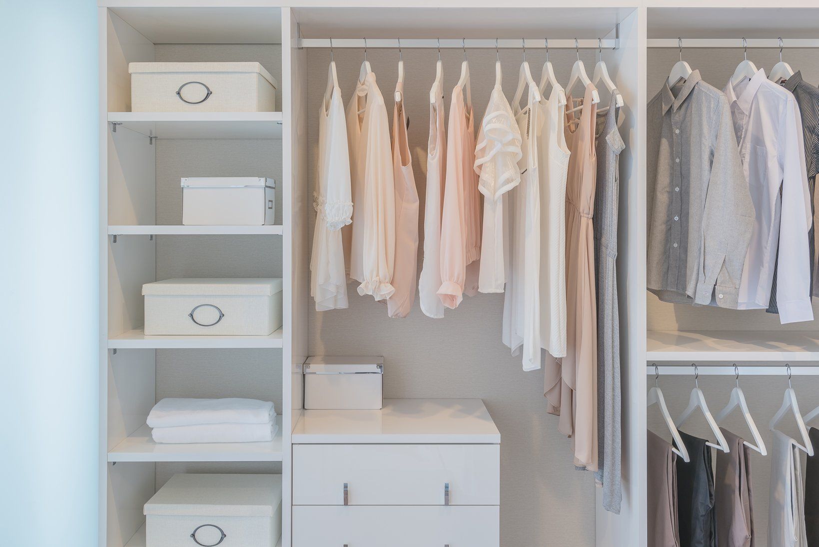clothes  hanging on rail in white wardrobe with boxes