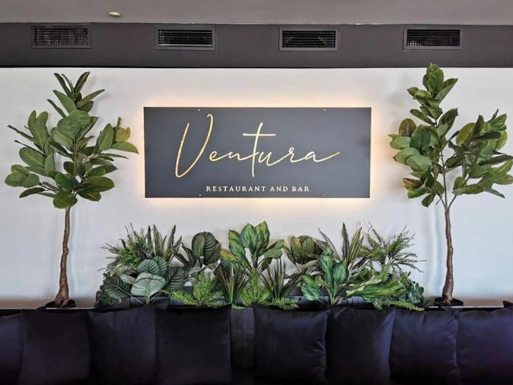 A Sign For Ventura Restaurant And Bar Is Surrounded By Plants — Mediterranean Food in Airlie Beach, QLD