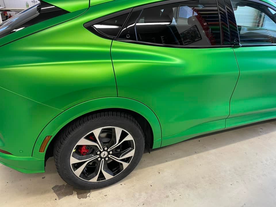 ein grünes Auto mit schwarzen Rädern sitzt auf einem Betonboden .