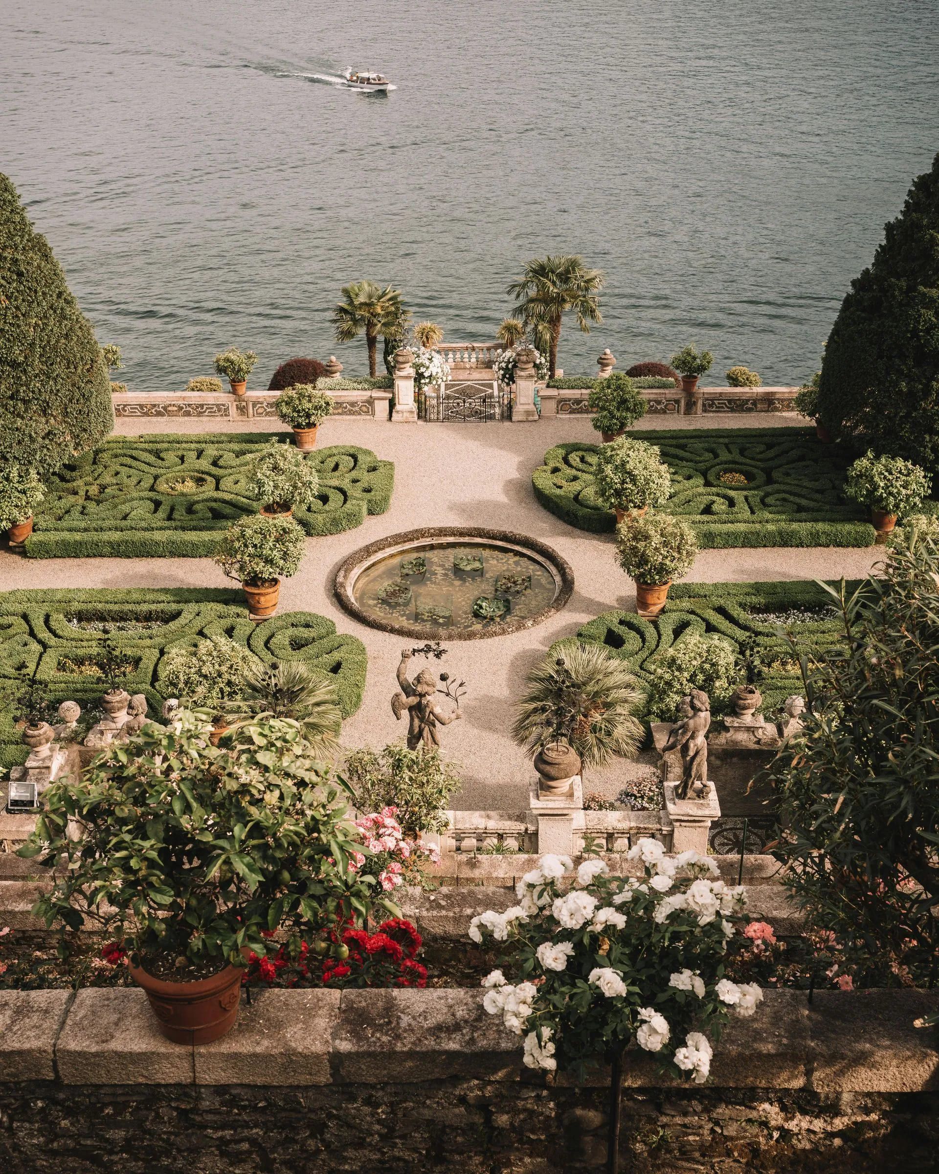 Una veduta aerea di un giardino con una fontana e una barca nell'acqua.