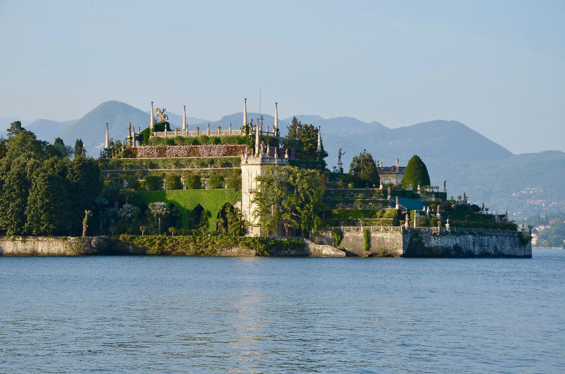 Una piccola isola in mezzo a un lago con le montagne sullo sfondo.