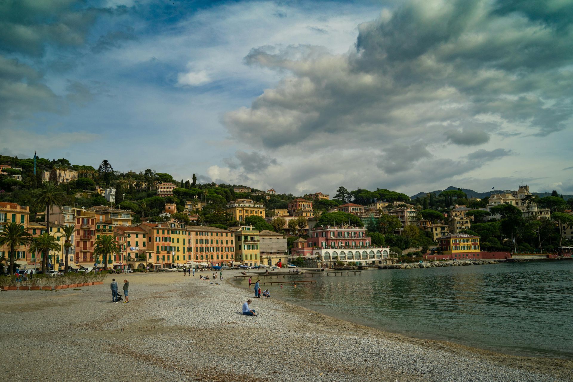 Una spiaggia con una città sullo sfondo e un cielo nuvoloso.