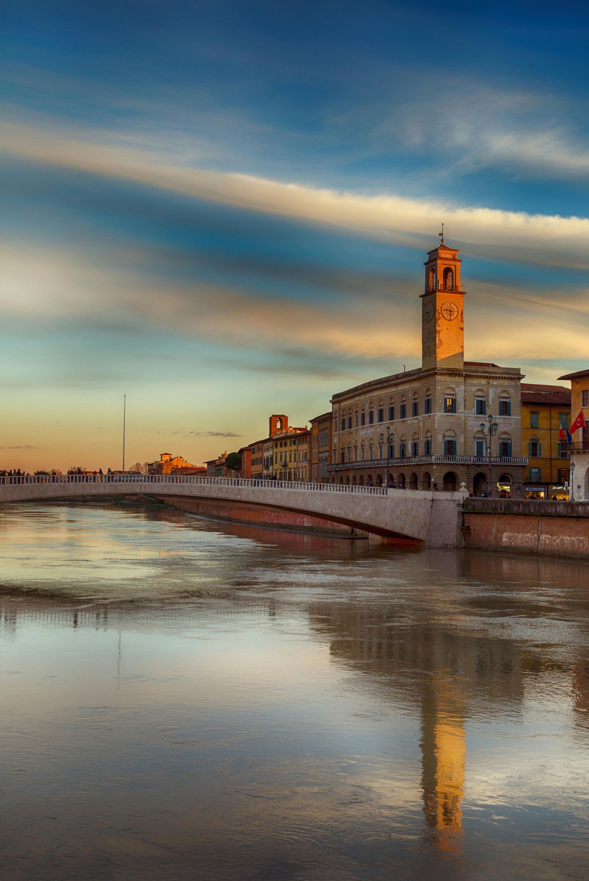 Un ponte sopra un fiume con una torre dell'orologio sullo sfondo