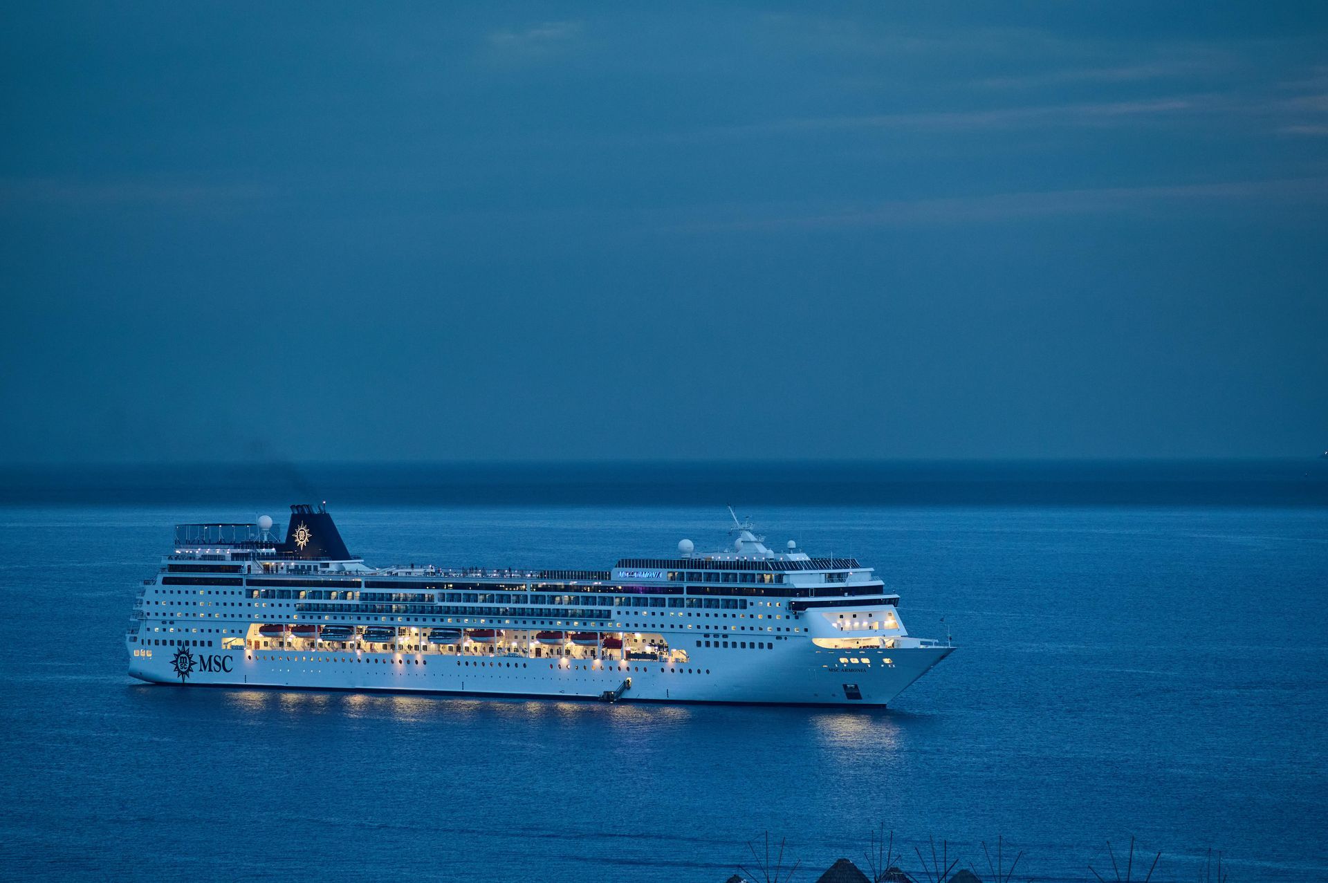 Una grande nave da crociera galleggia su uno specchio d'acqua di notte.