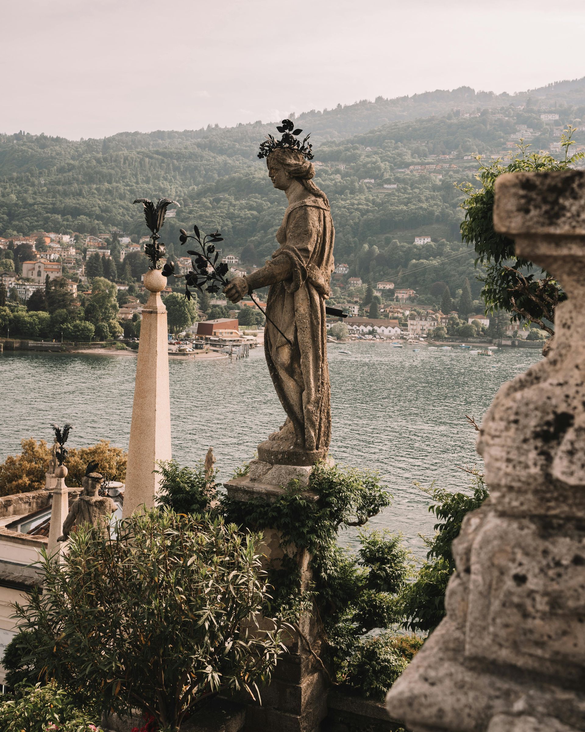 C'è una statua di una donna che tiene dei fiori davanti a un lago.