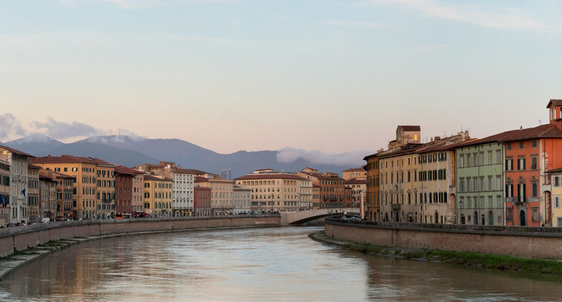 Un fiume attraversa una città con le montagne sullo sfondo.