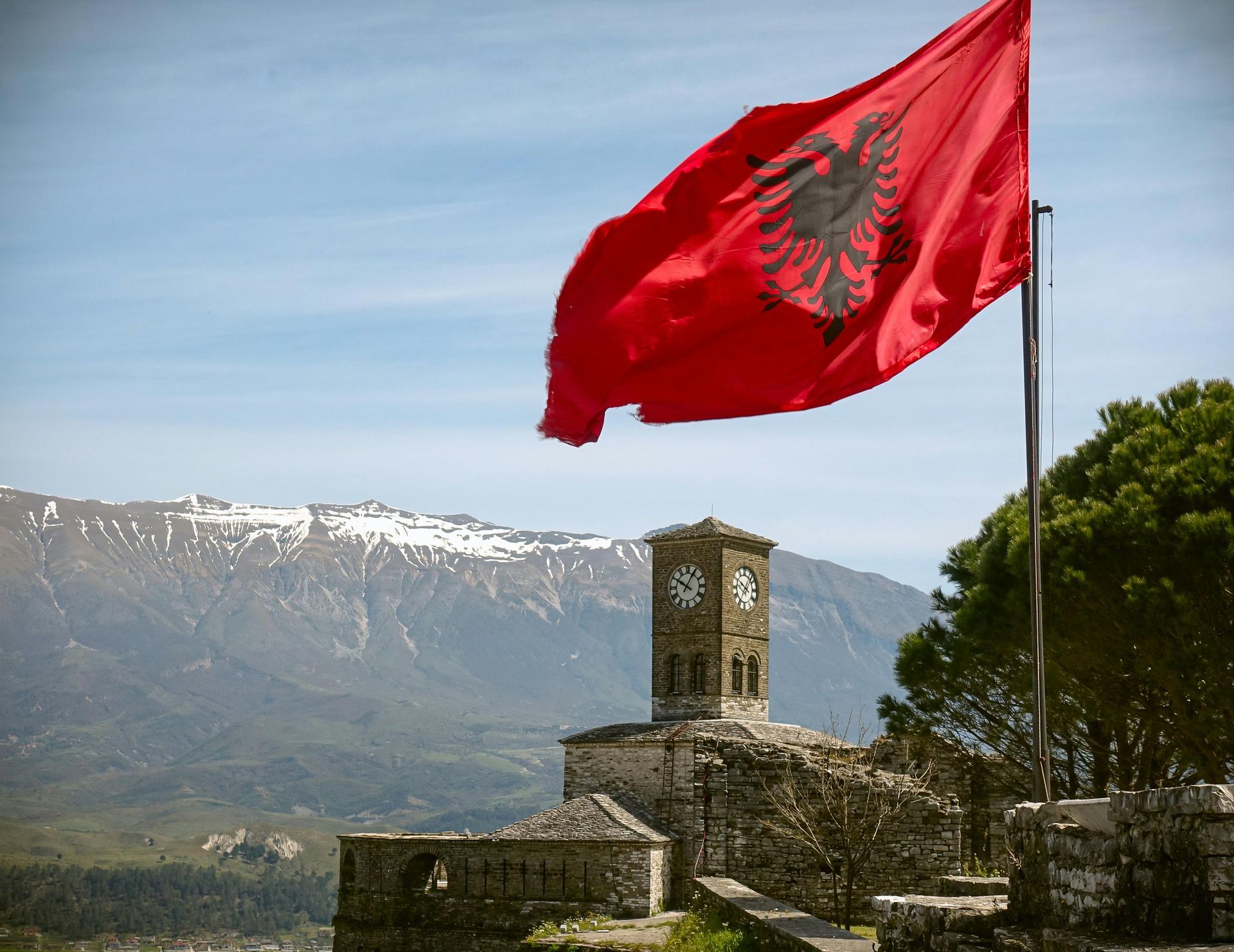 Una bandiera albanese con un'aquila sopra sventola davanti a una torre dell'orologio