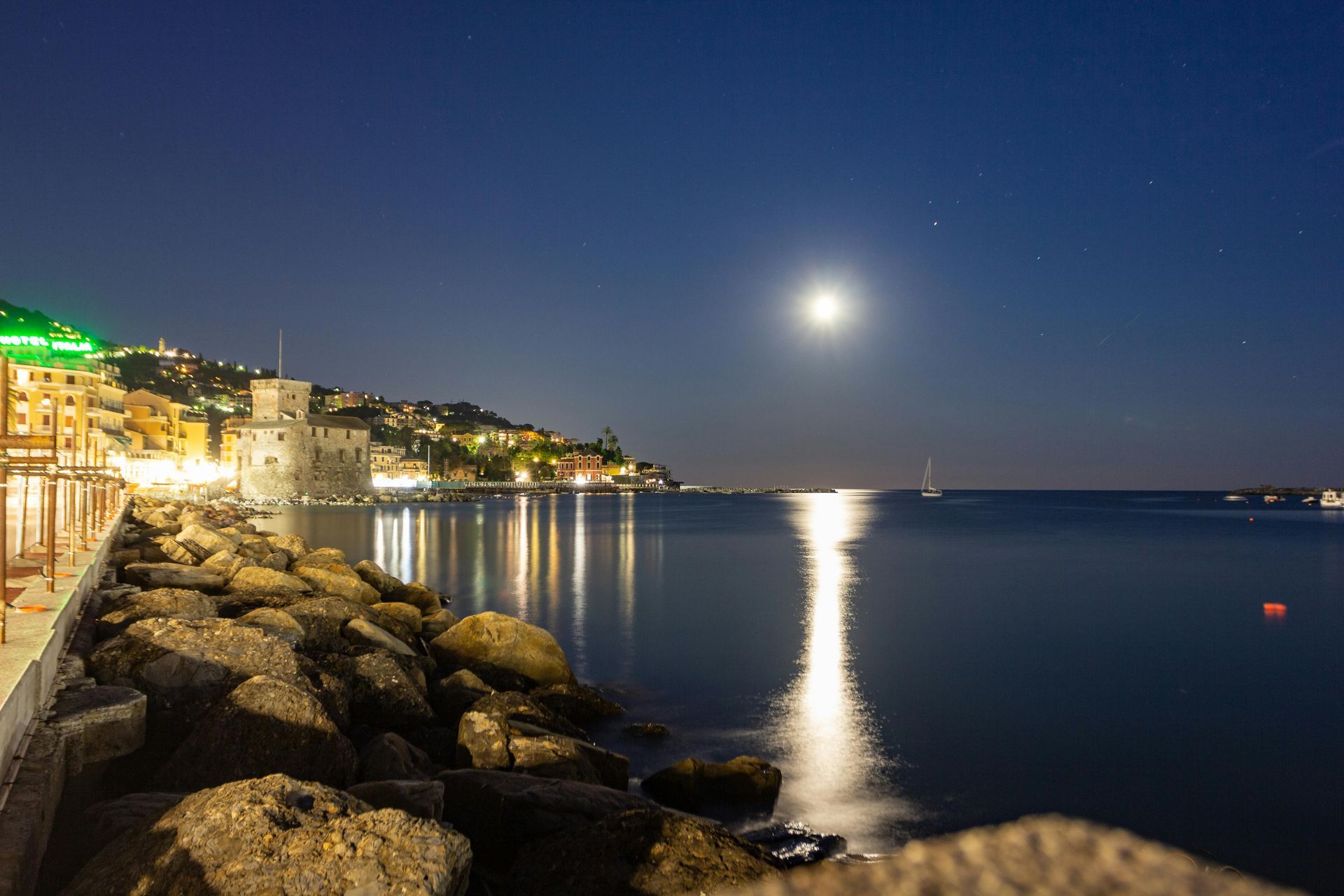 Una luna piena splende su uno specchio d'acqua di notte.