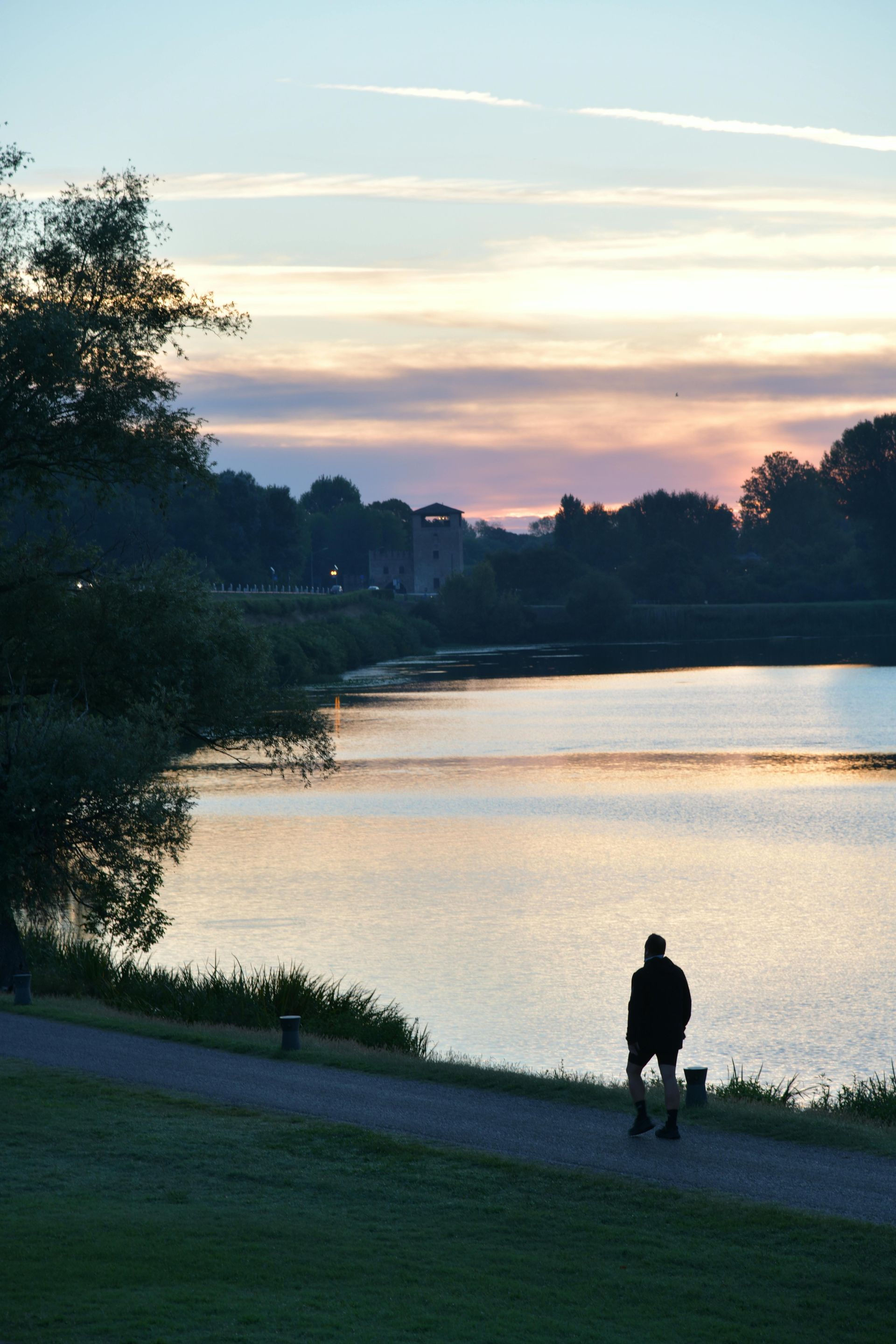 Un uomo che cammina lungo un sentiero accanto a un lago al tramonto