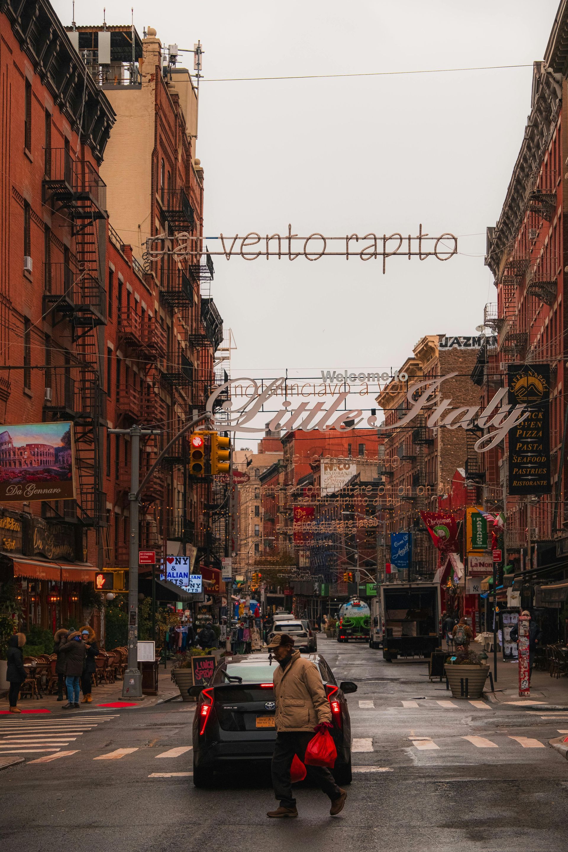 Un uomo cammina lungo una trafficata strada cittadina accanto a un'auto.