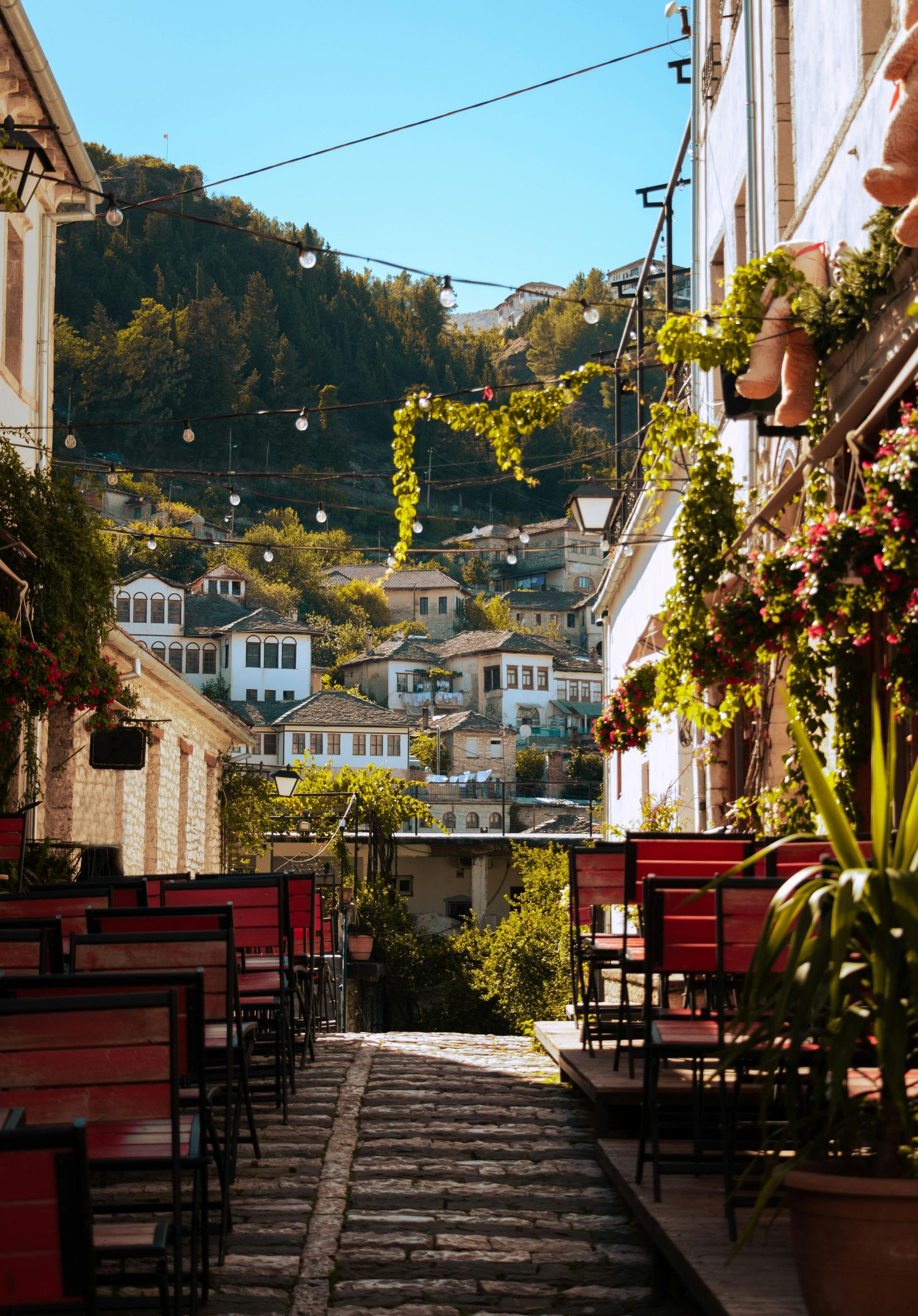 Uno stretto vicolo con tavoli e sedie e una vista sulla città.