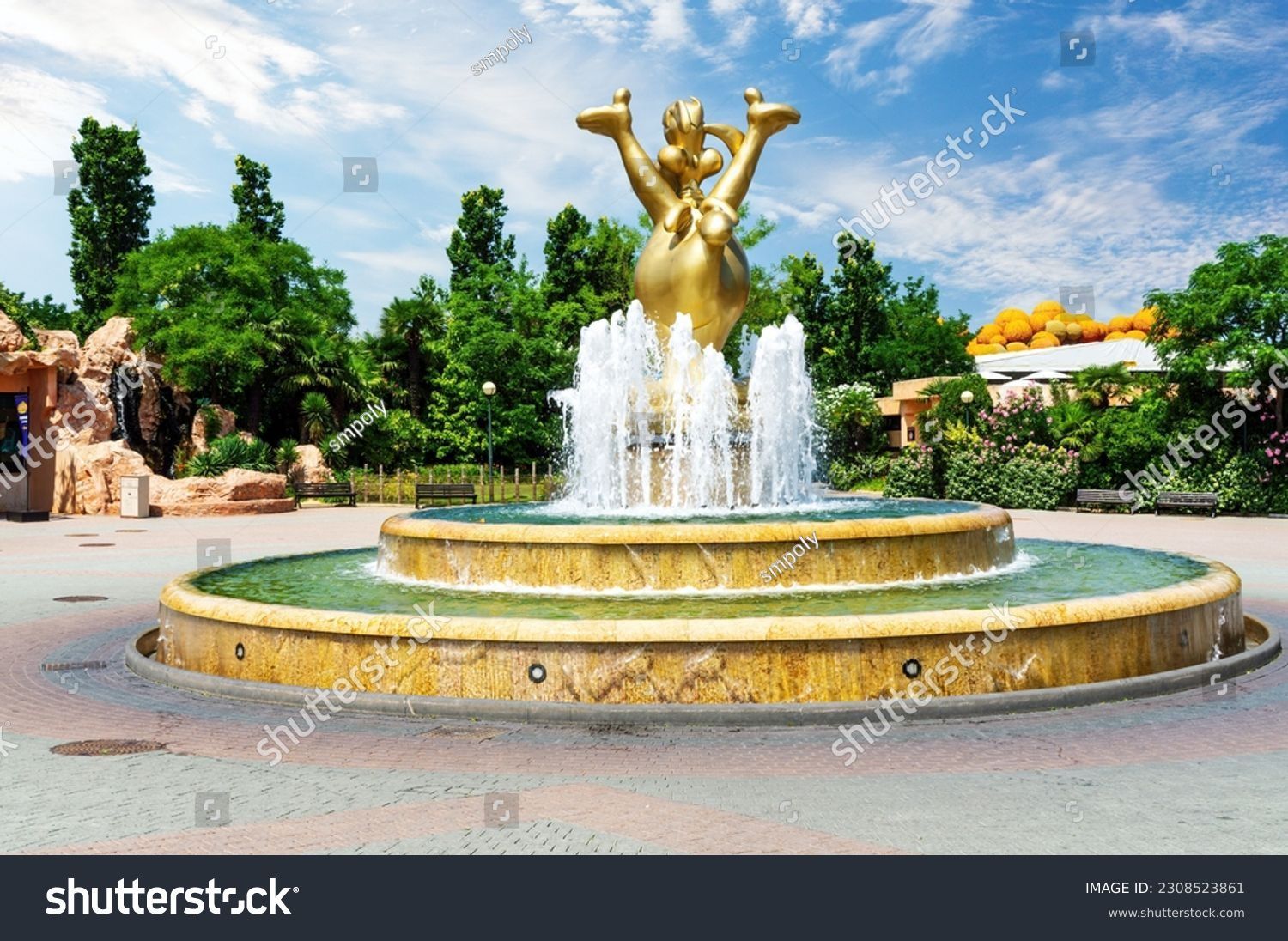 Una fontana con al centro una statua di Topolino in un parco.