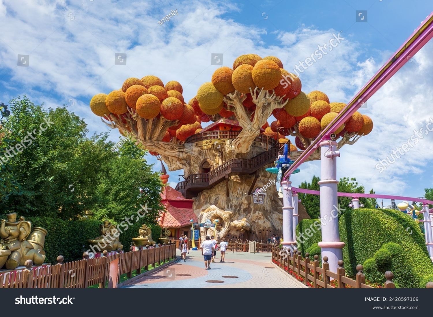 Montagne russe in un parco divertimenti con un albero sullo sfondo.