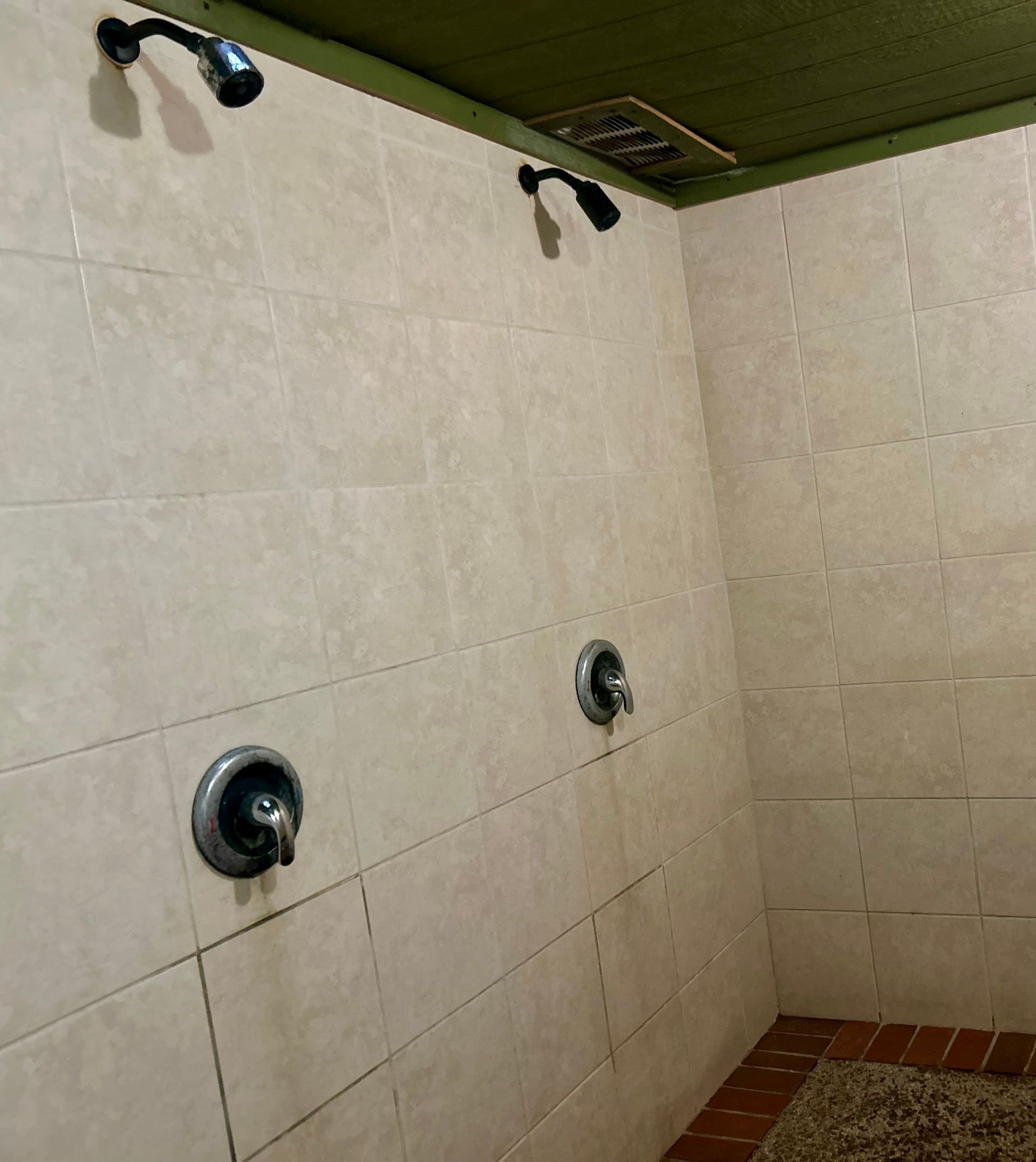 A bathroom with three shower heads on the wall