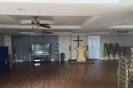 A room with tables and chairs and a cross on the wall