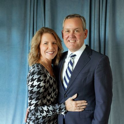 A man in a suit and tie is standing next to a woman in a green dress.