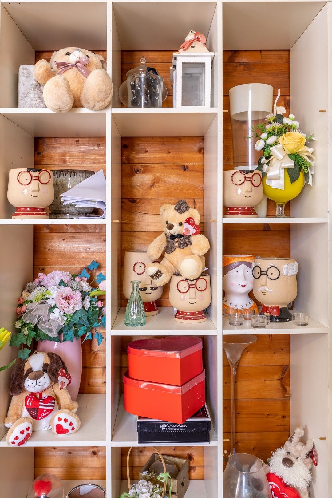 Uno scaffale pieno di animali di peluche e fiori.