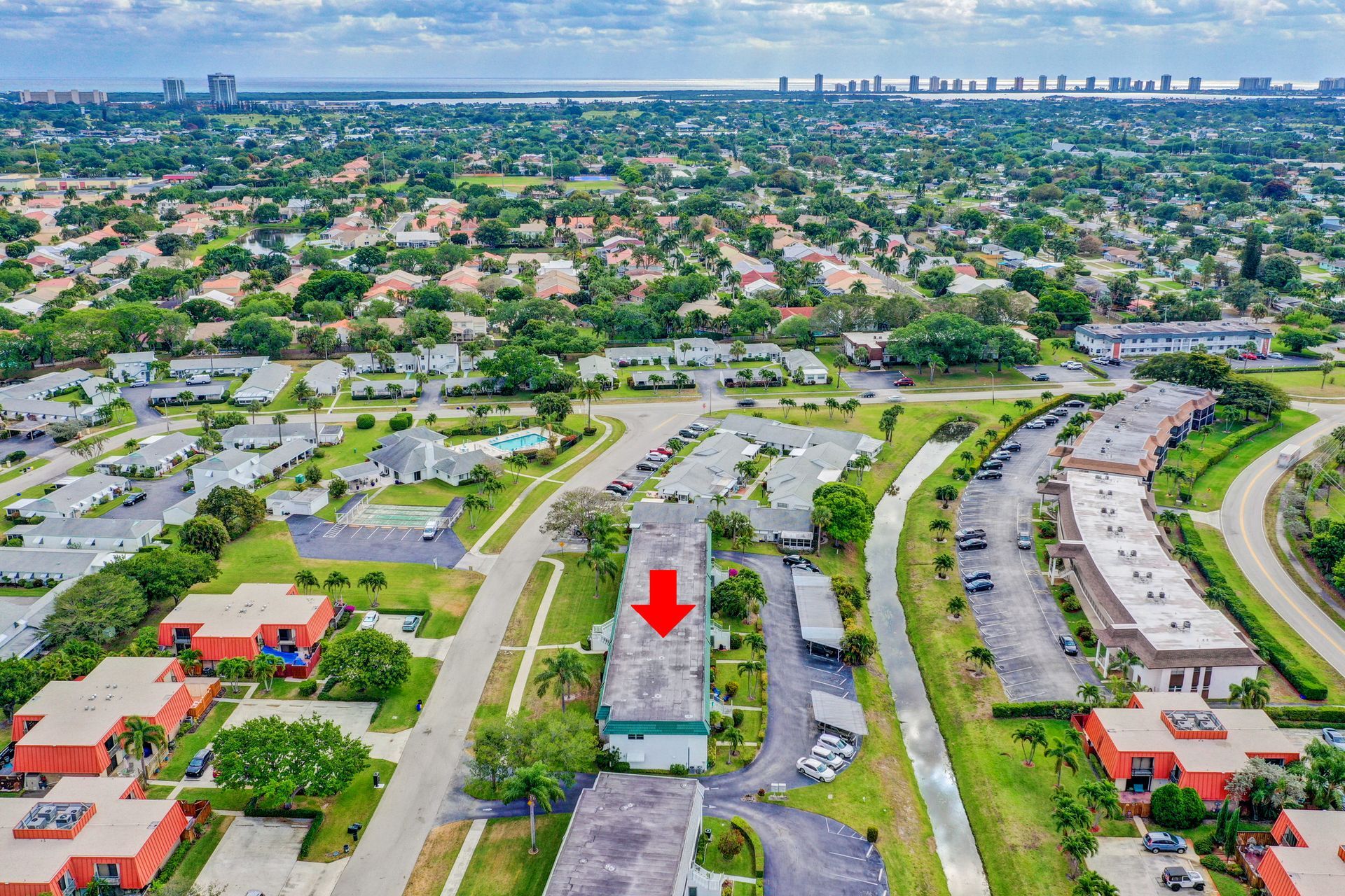 An aerial view of a residential area with a red arrow pointing to a building.