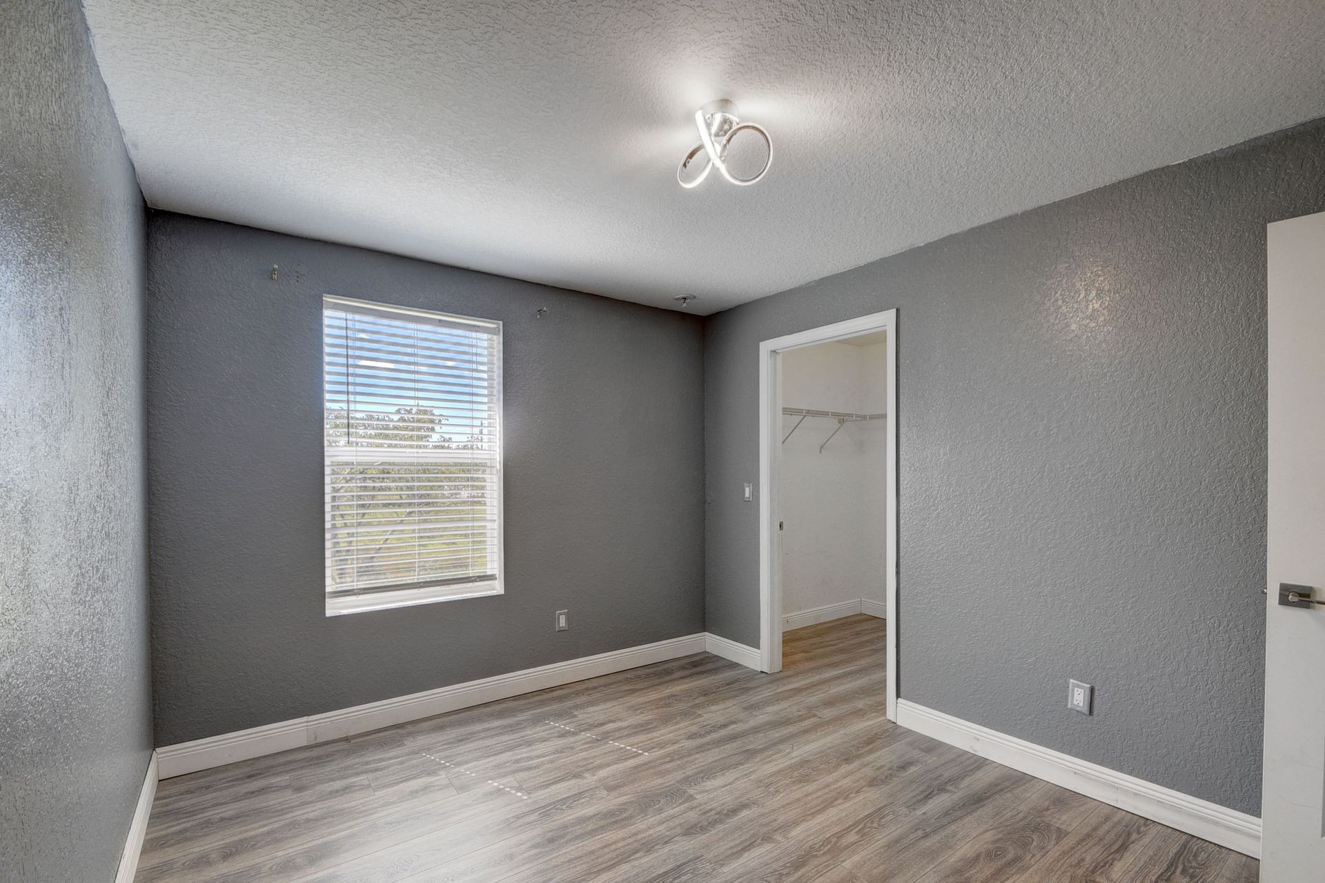 An empty bedroom with a window and a walk in closet.