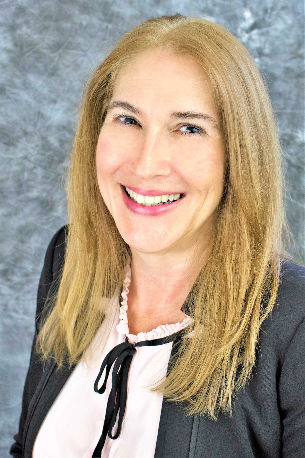A woman with long blonde hair is smiling for the camera.