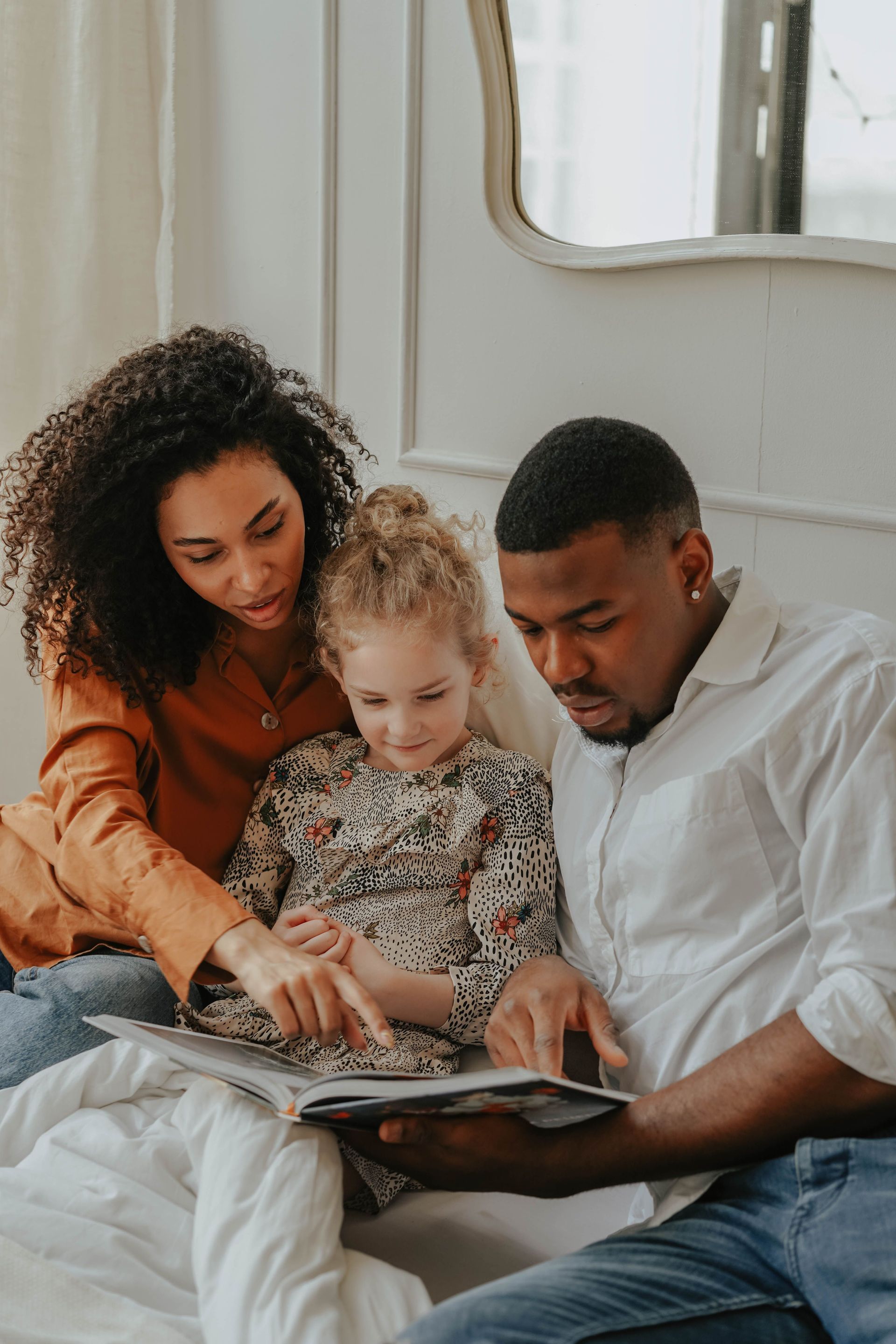 Family reading a book together on a couch in a bright living room