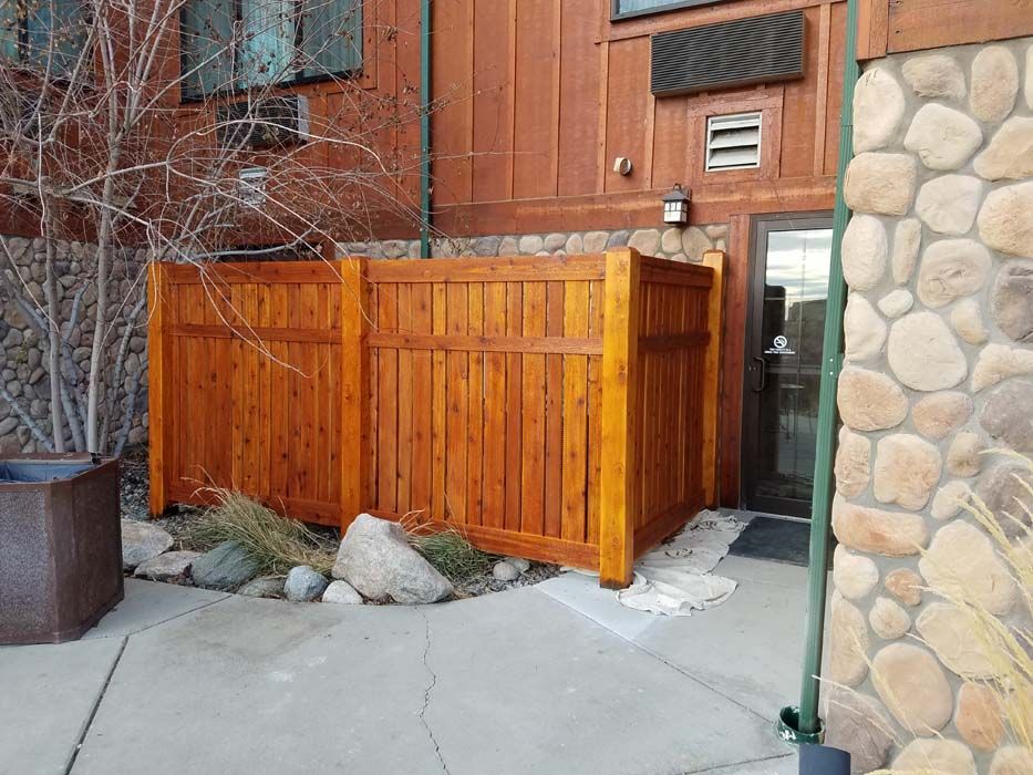 A wooden fence is sitting in front of a stone building.