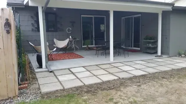 A patio with a table and chairs under a covered porch.