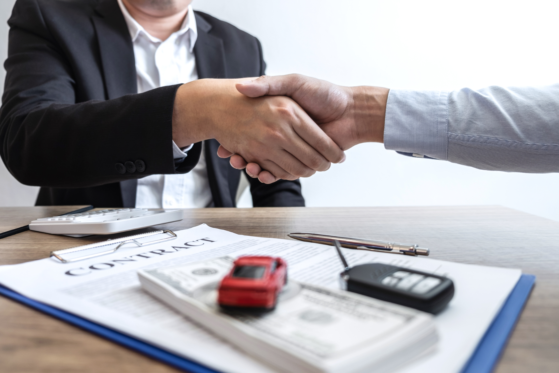 Red car with severe damage to the rear, loaded on a tow truck.