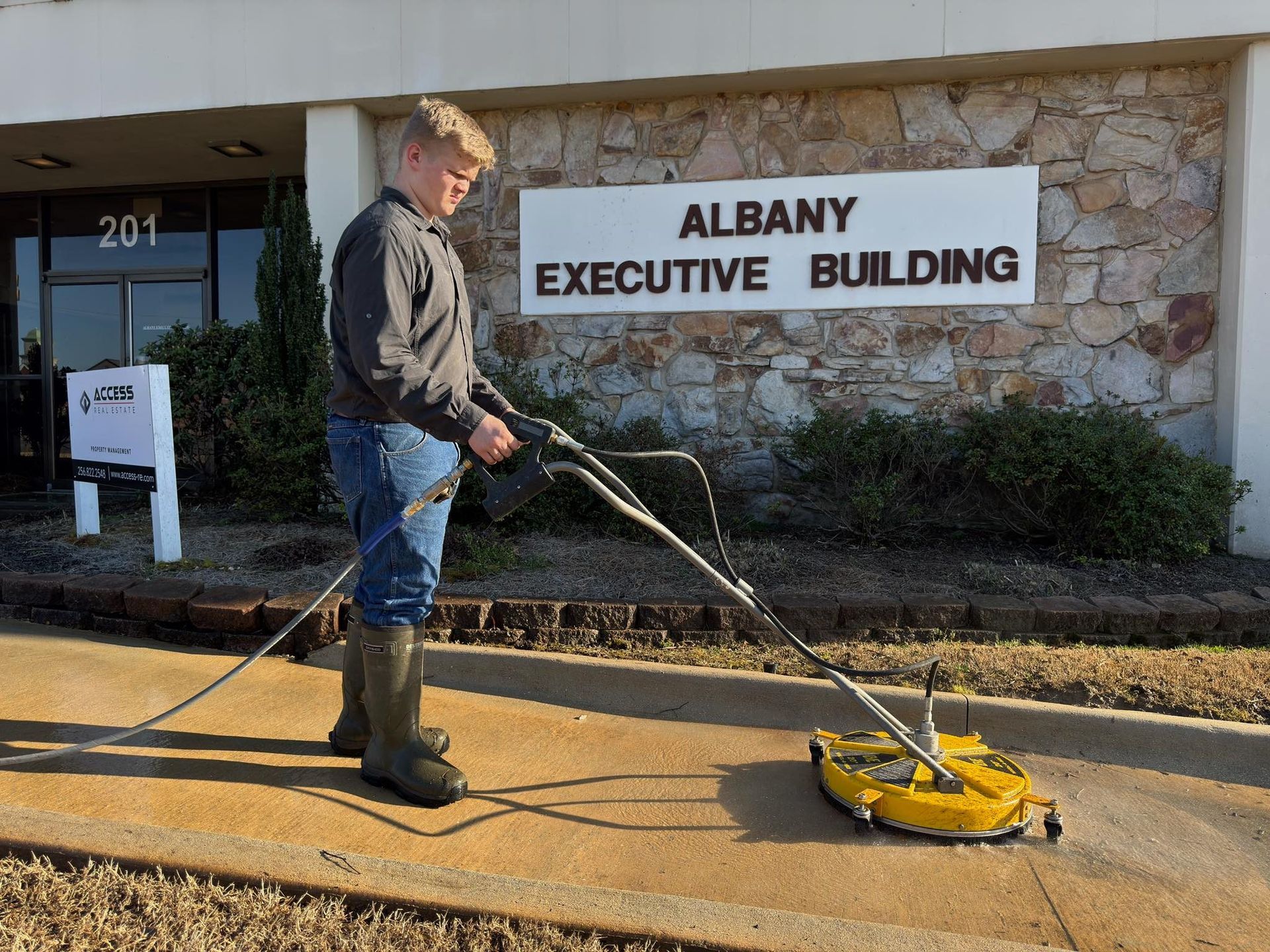 Electrician in a safety vest and helmet inspects electrical panel.