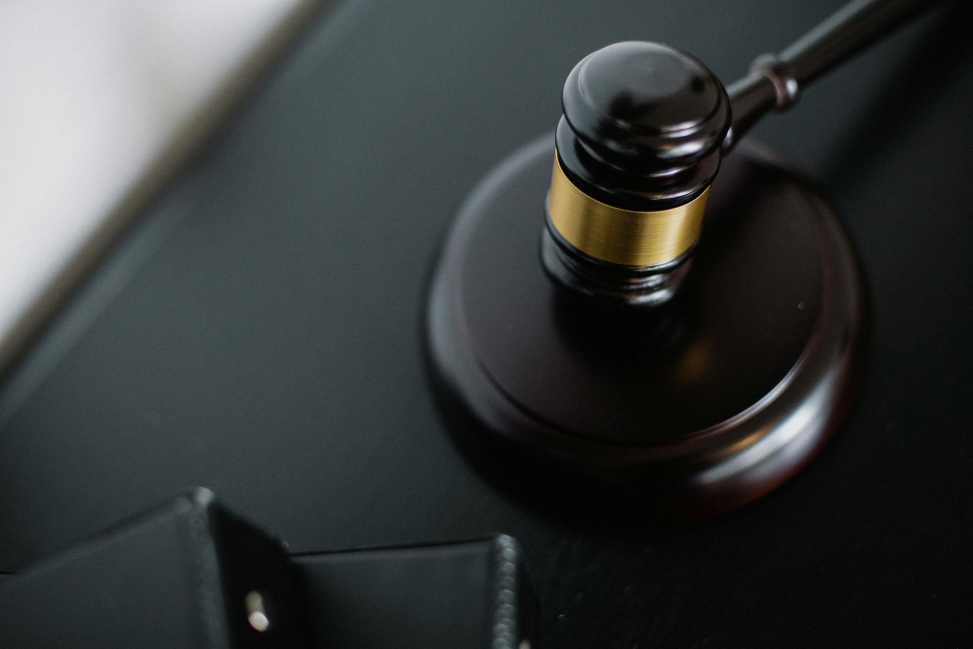 Wooden gavel on a black surface, near a binder.