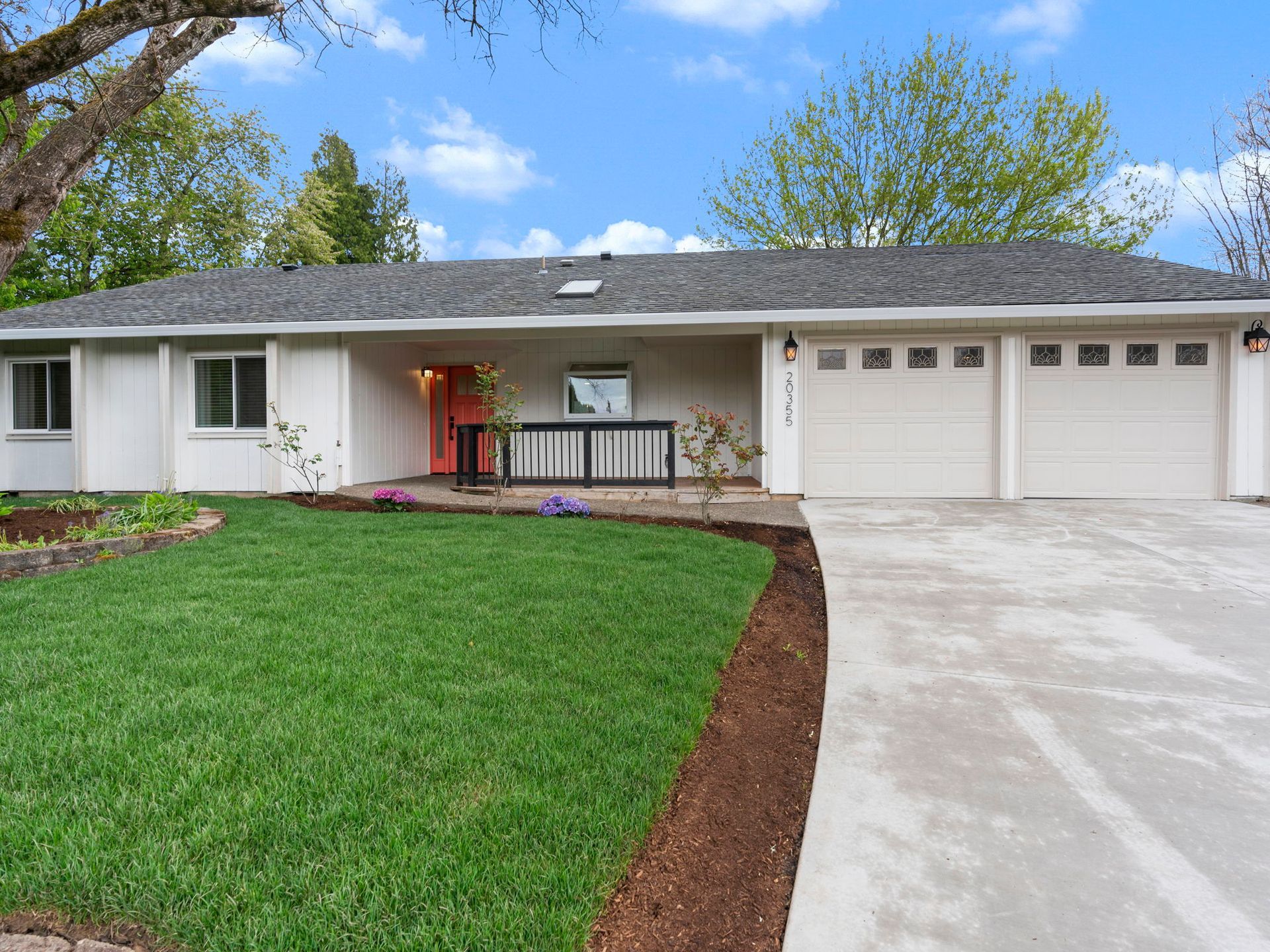 A white house with a concrete driveway leading to it