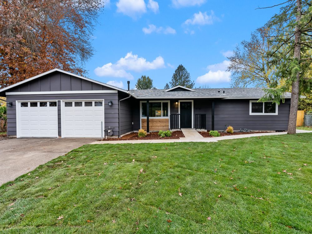 The front of a house with a large lawn and two garage doors.