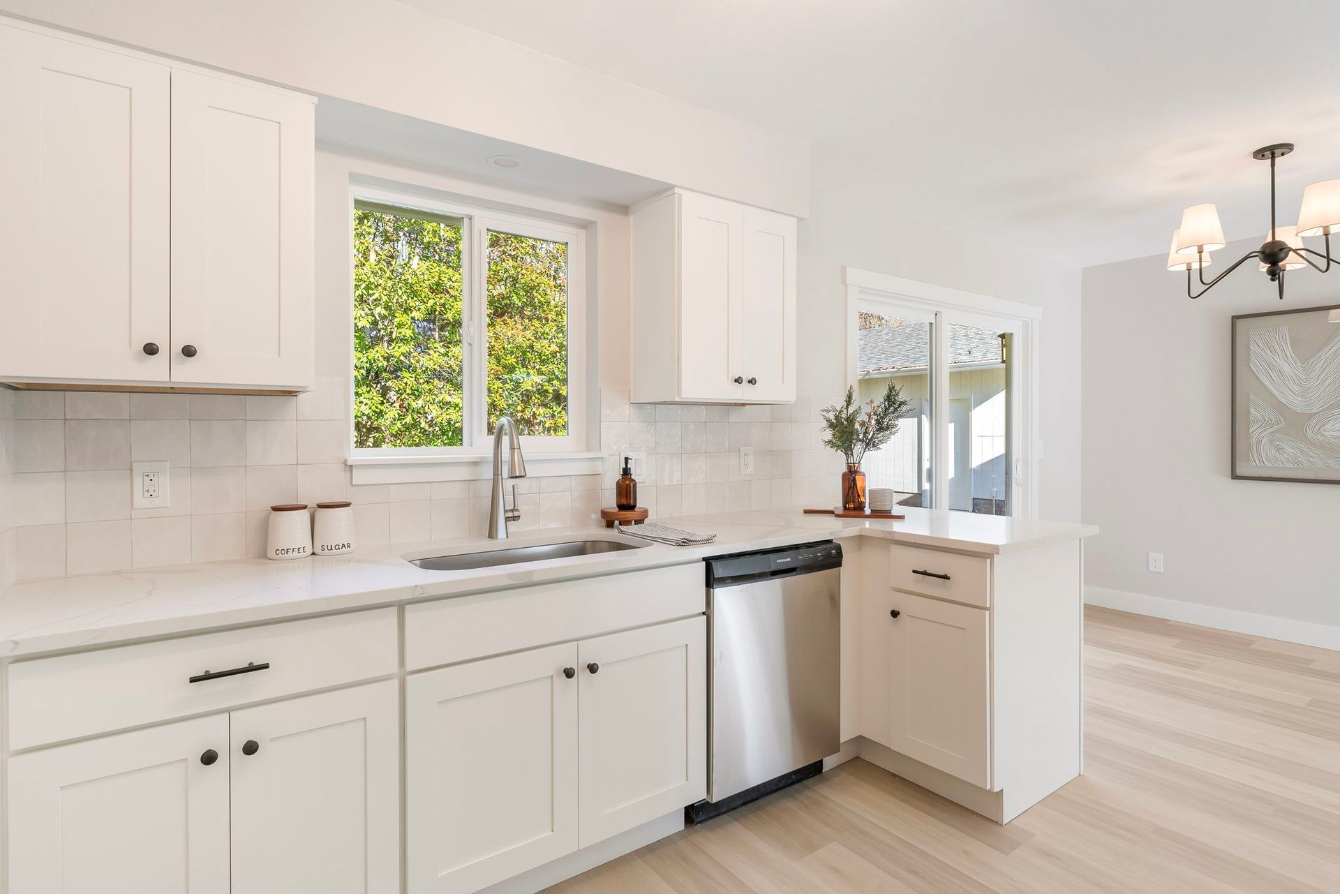 A kitchen with white cabinets , stainless steel appliances , a sink , and a window.