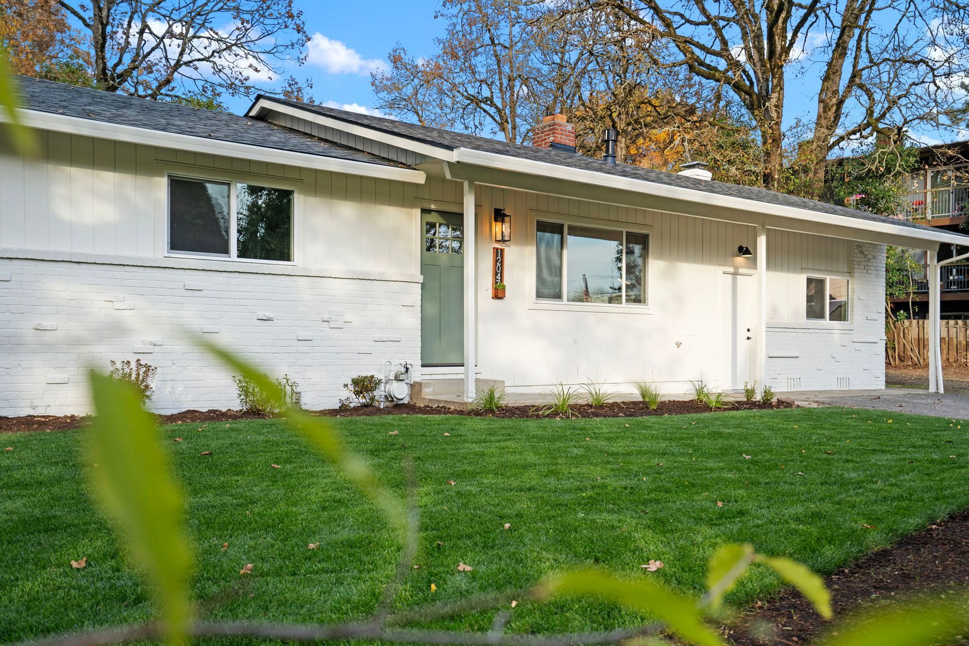 A white house with a lush green lawn in front of it.