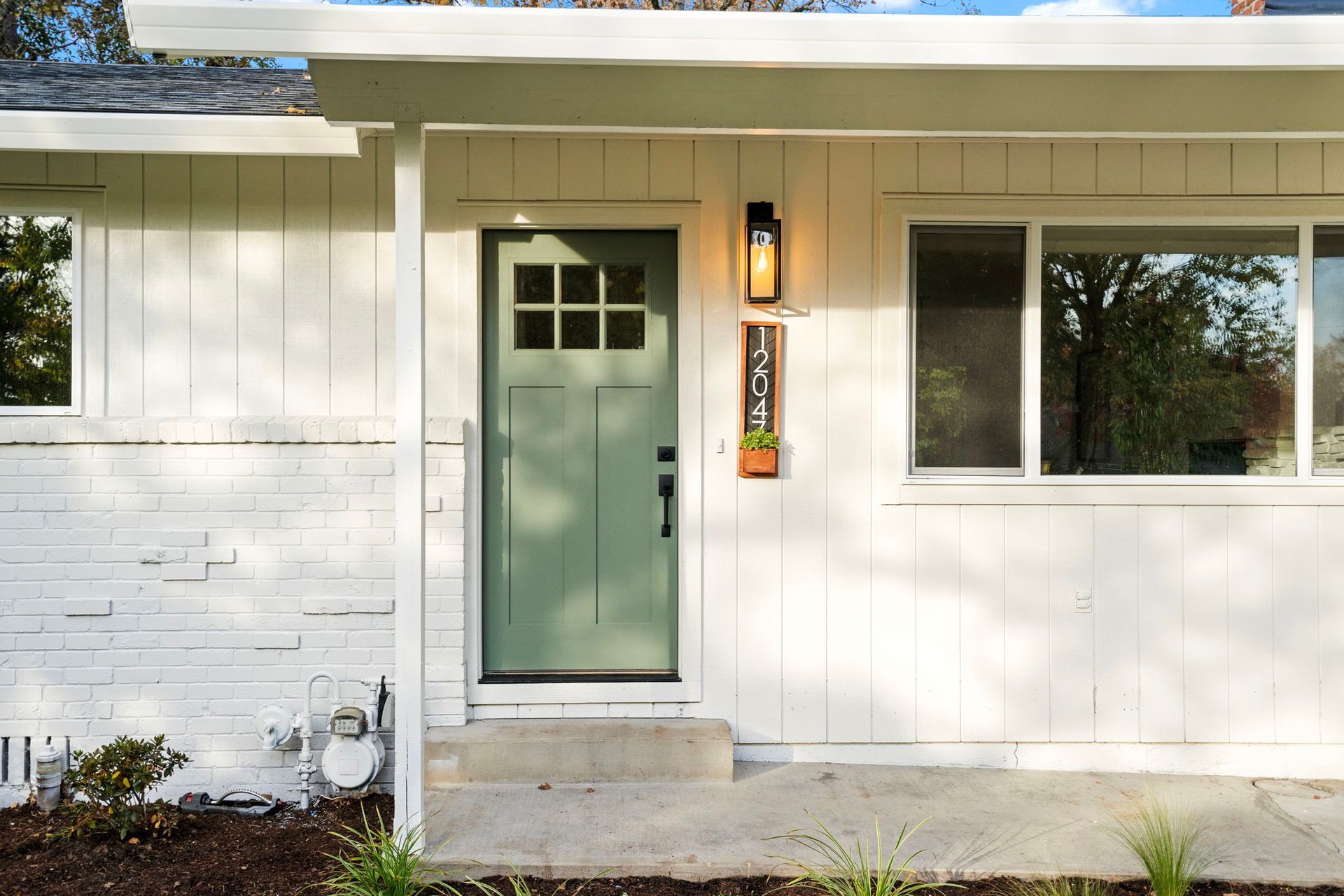 The front of a white house with a green door