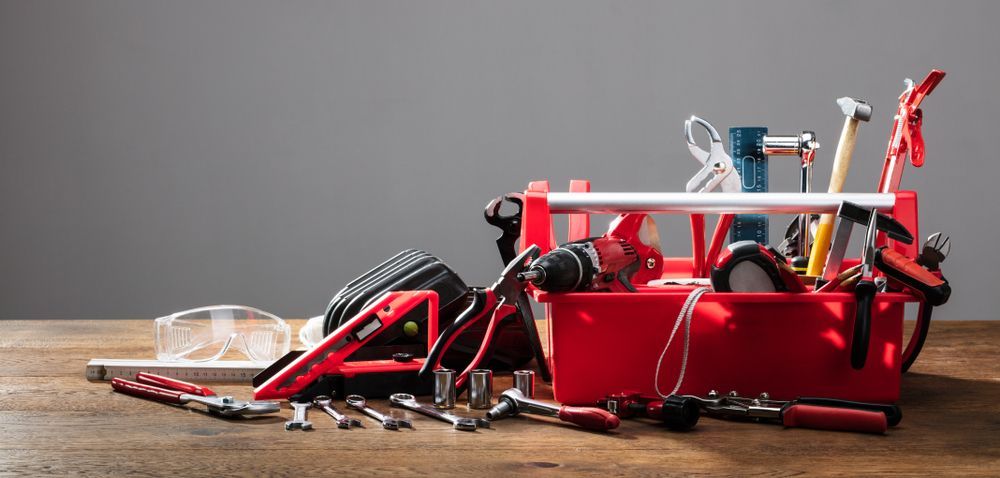 A Red Toolbox Filled With Tools is Sitting on a Wooden Table — Hothams In Bathurst, NSW