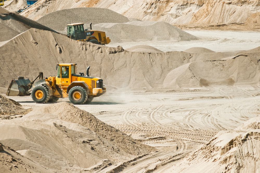 A Yellow Bulldozer is Driving Through a Pile of Sand — Hothams In Orange, NSW