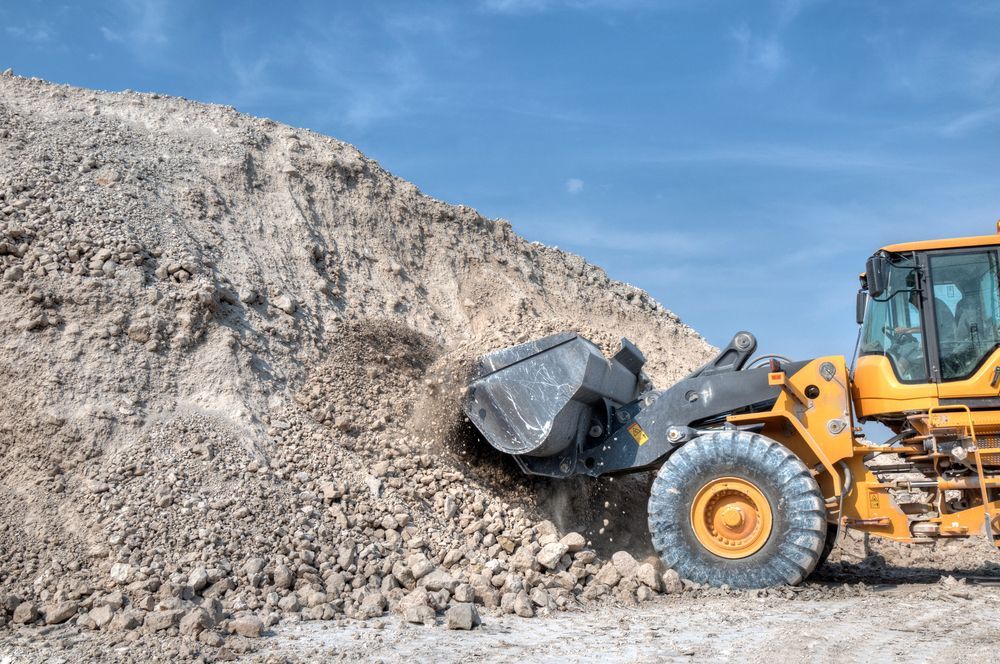 A Bulldozer is Loading Gravel Into a Bucket on Top of a Pile of Gravel — Hothams In Dubbo, NSW