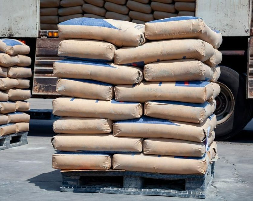 A Pallet of Bags of Cement is Stacked on Top of Each Other in Front of a Truck — Hothams In Orange, NSW