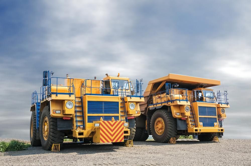 Two Yellow Dump Trucks Are Parked Next to Each Other on a Dirt Road — Hothams In Mudgee, NSW