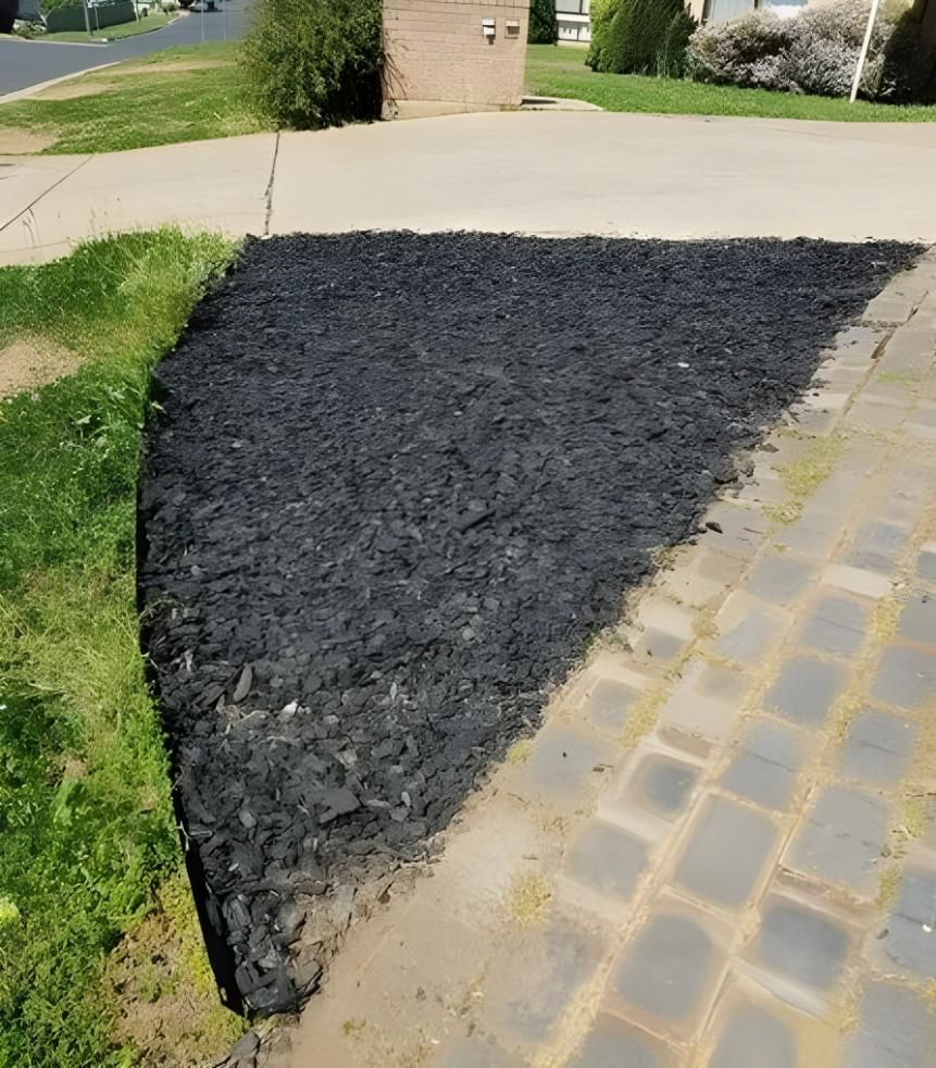 A Pile of Black Mulch is on the Side of a Driveway — Hothams In Bathurst, NSW