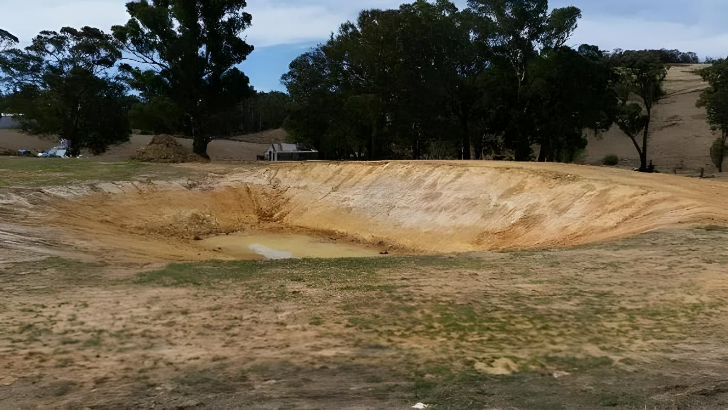 A Large Hole in the Middle of a Field With Trees in the Background — Hothams In Bathurst, NSW
