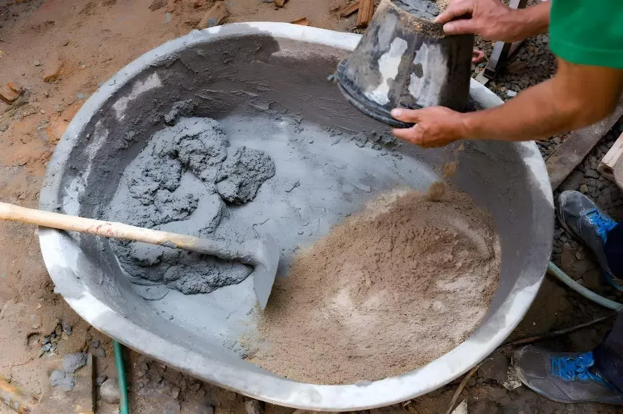 A Person is Mixing Concrete in a Large Bowl With a Shovel — Hothams In Bathurst, NSW