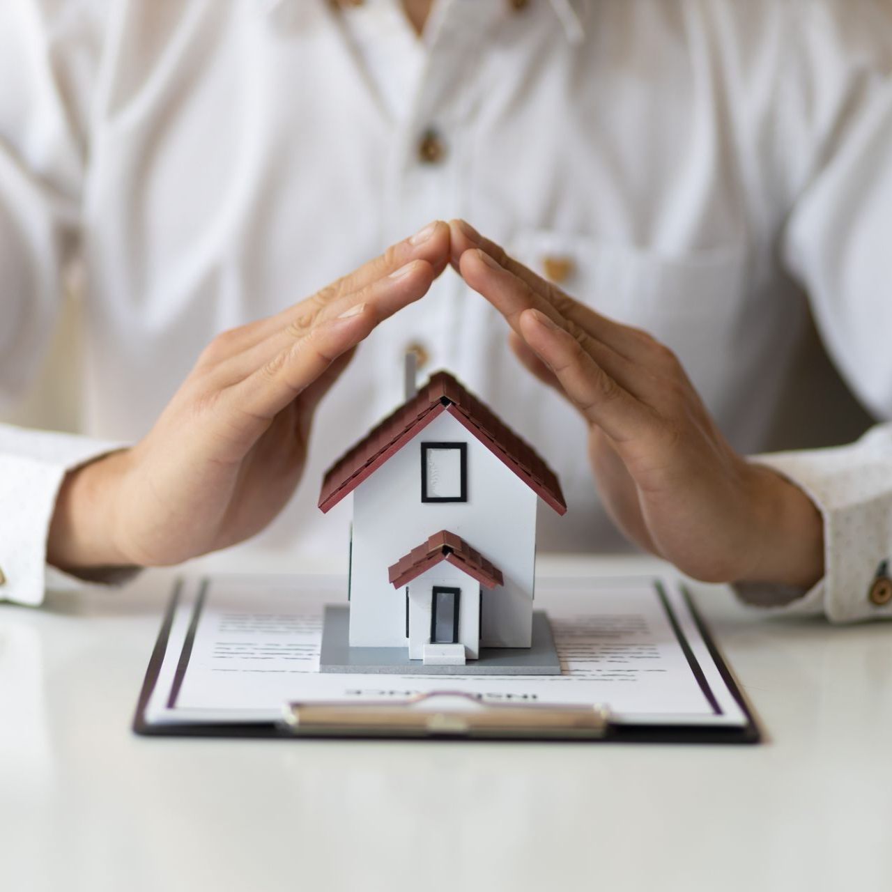 Cropped view of an agent from a local insurance agency, with a contract and a house model. Cropped view of an agent from a local insurance agency, with a contract and a house model.