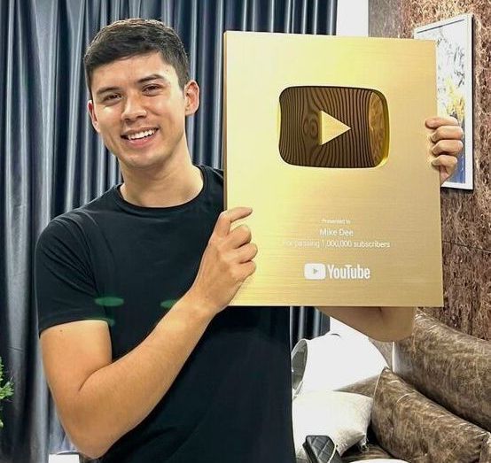 A young man is holding a gold youtube award in his hands.