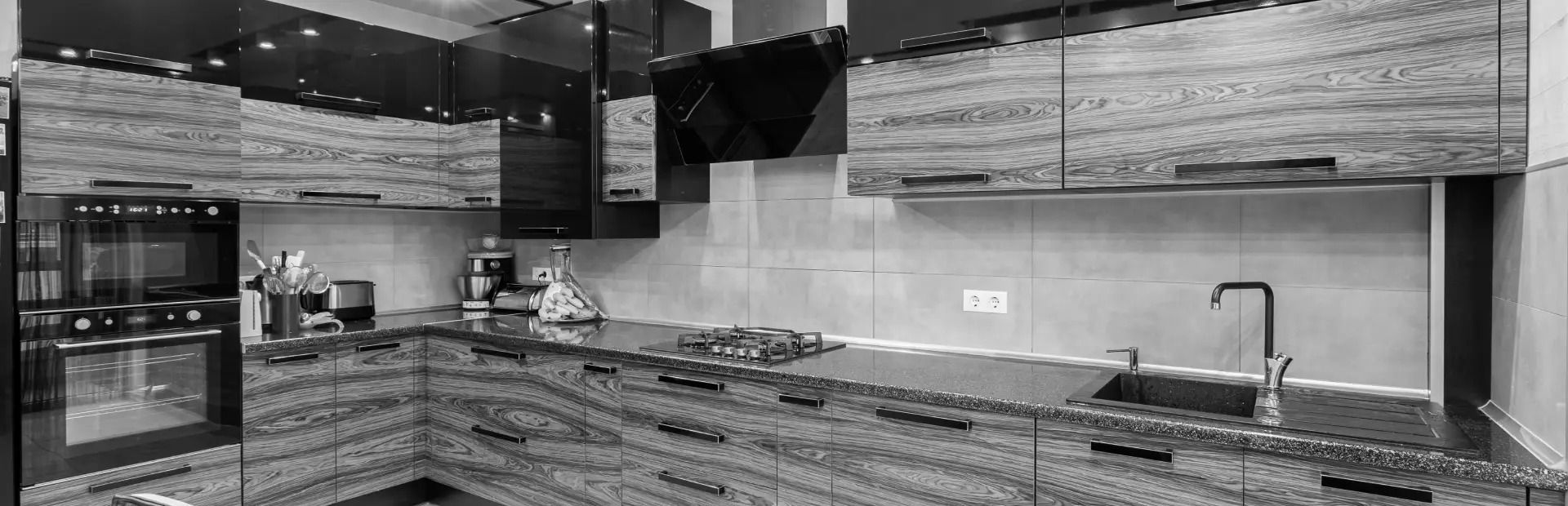 A black and white photo of a kitchen with granite counter tops and cabinets.