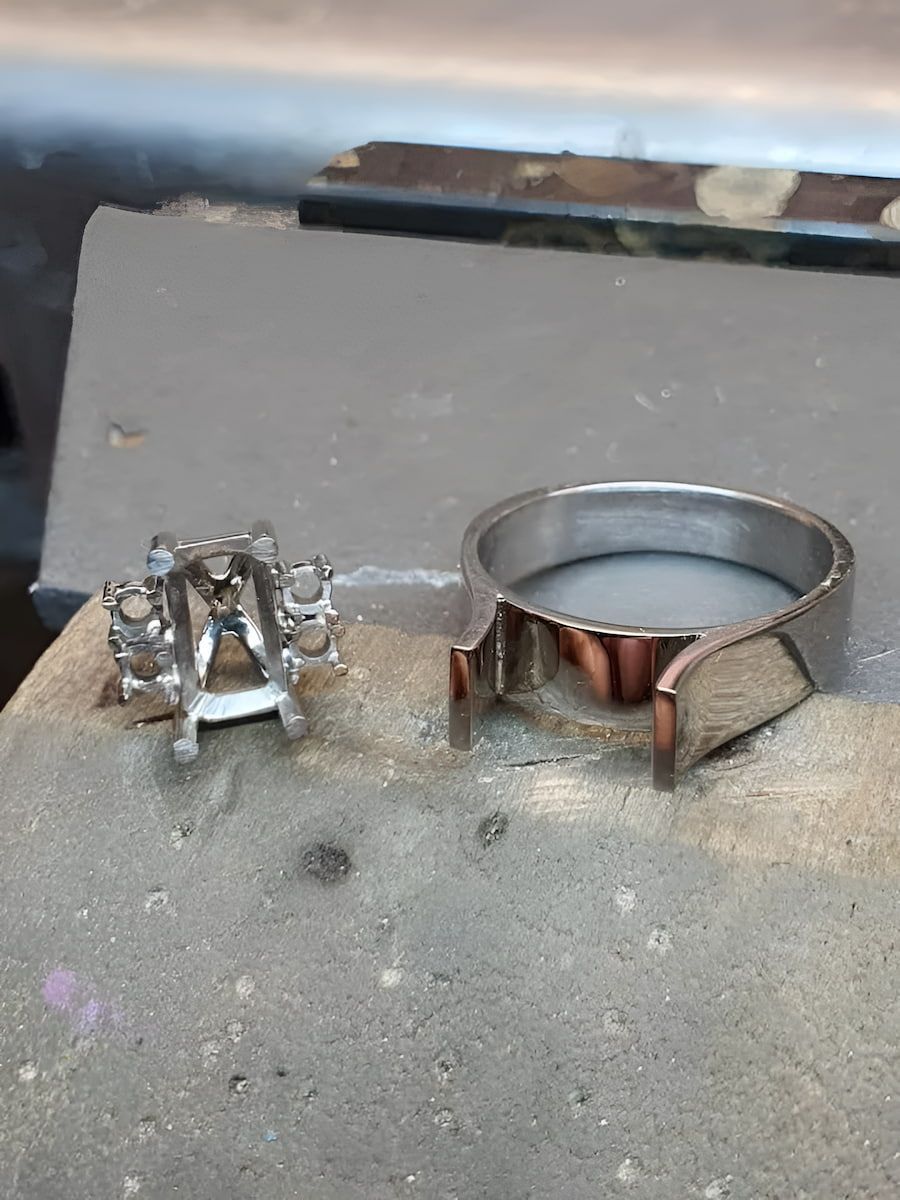 Two Silver Metal Ring Components on a Gray Workbench — Chris Williams Retail & Manufacturing Jewellers in Wanguri, NT