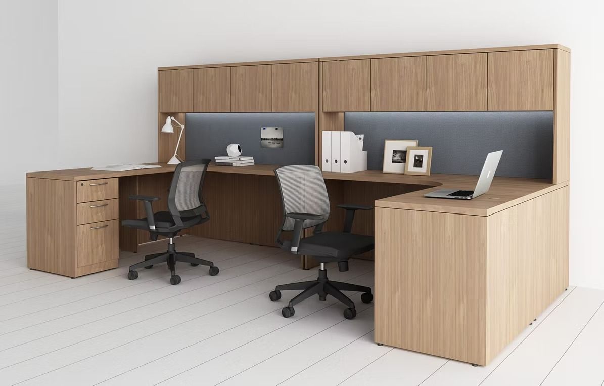 A wooden office cubicle with two desks and two chairs.