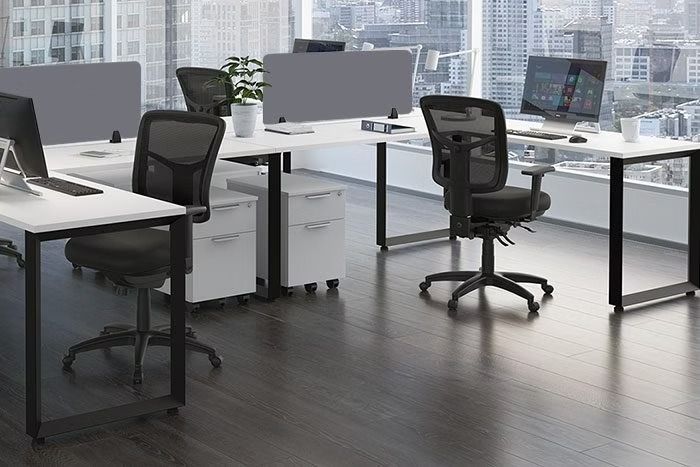 A row of desks and chairs in an office with computers.