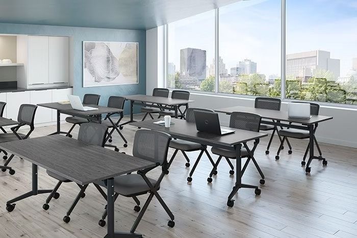 A classroom with tables and chairs and a lot of windows.